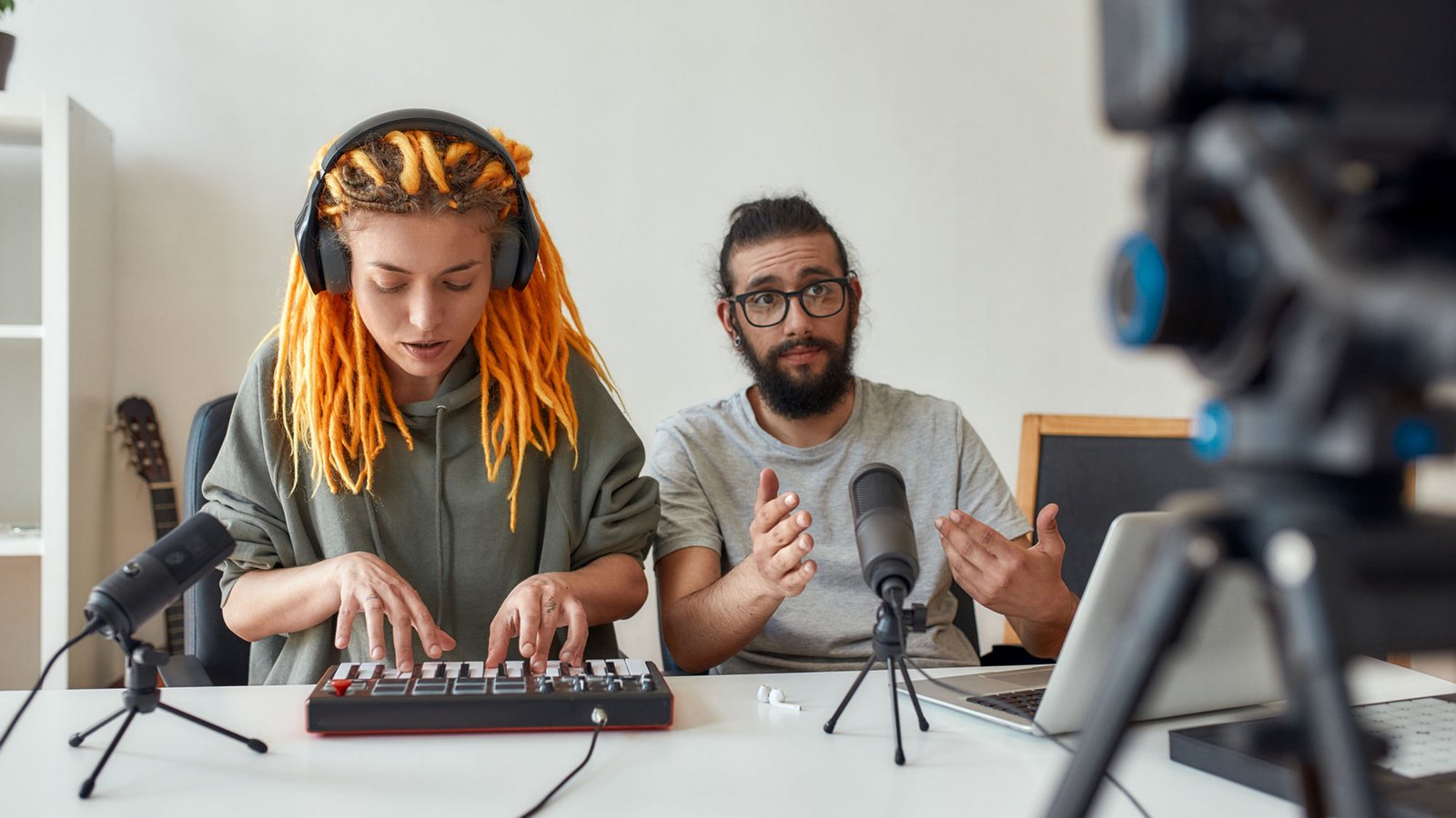 A student playing a keyboard while Caroline listens, with a camera set up to record the session