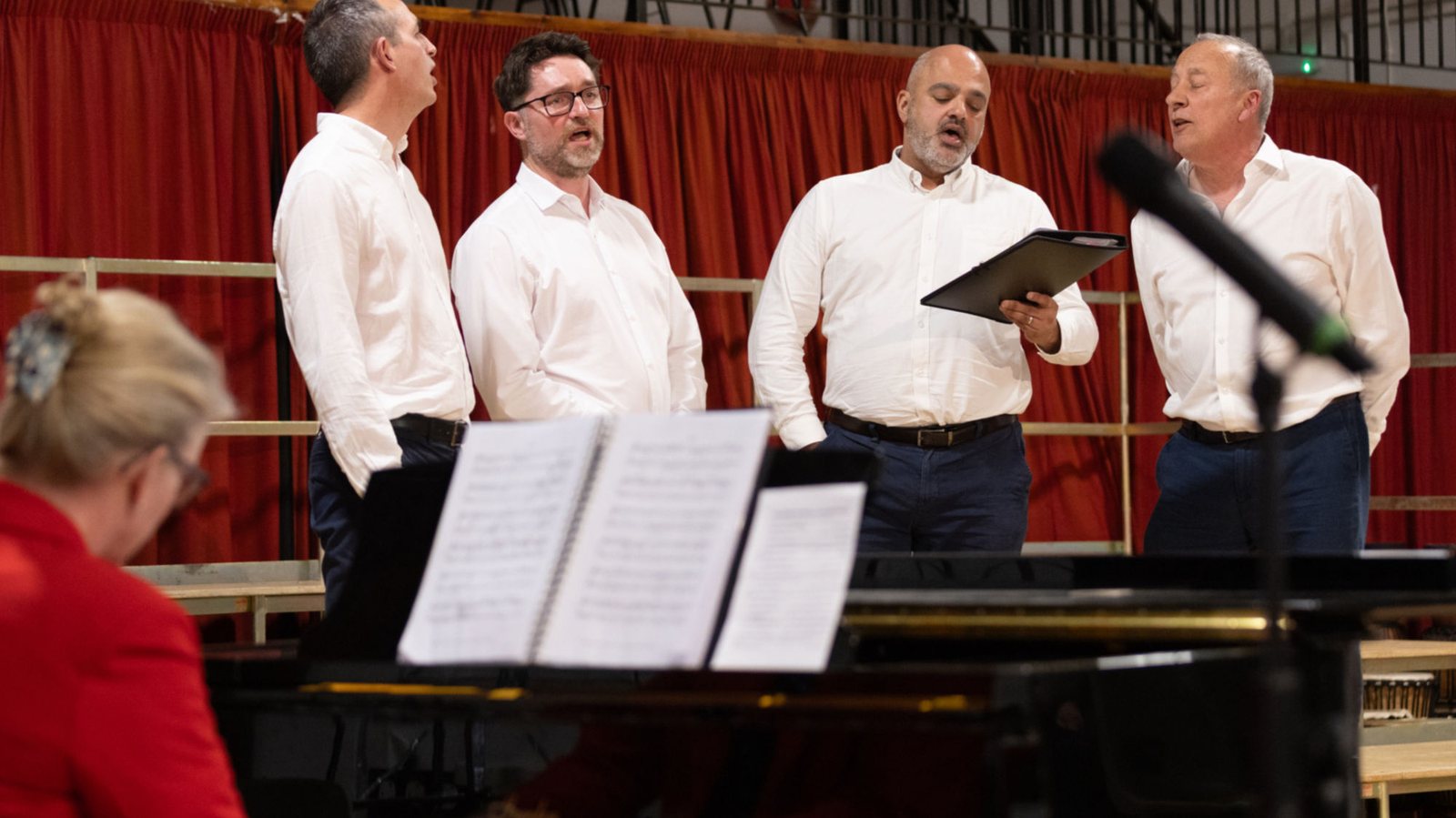 Singers performing beside a grand piano