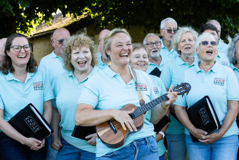 Choir members in Sound Engine polo shirts holding ukuleles