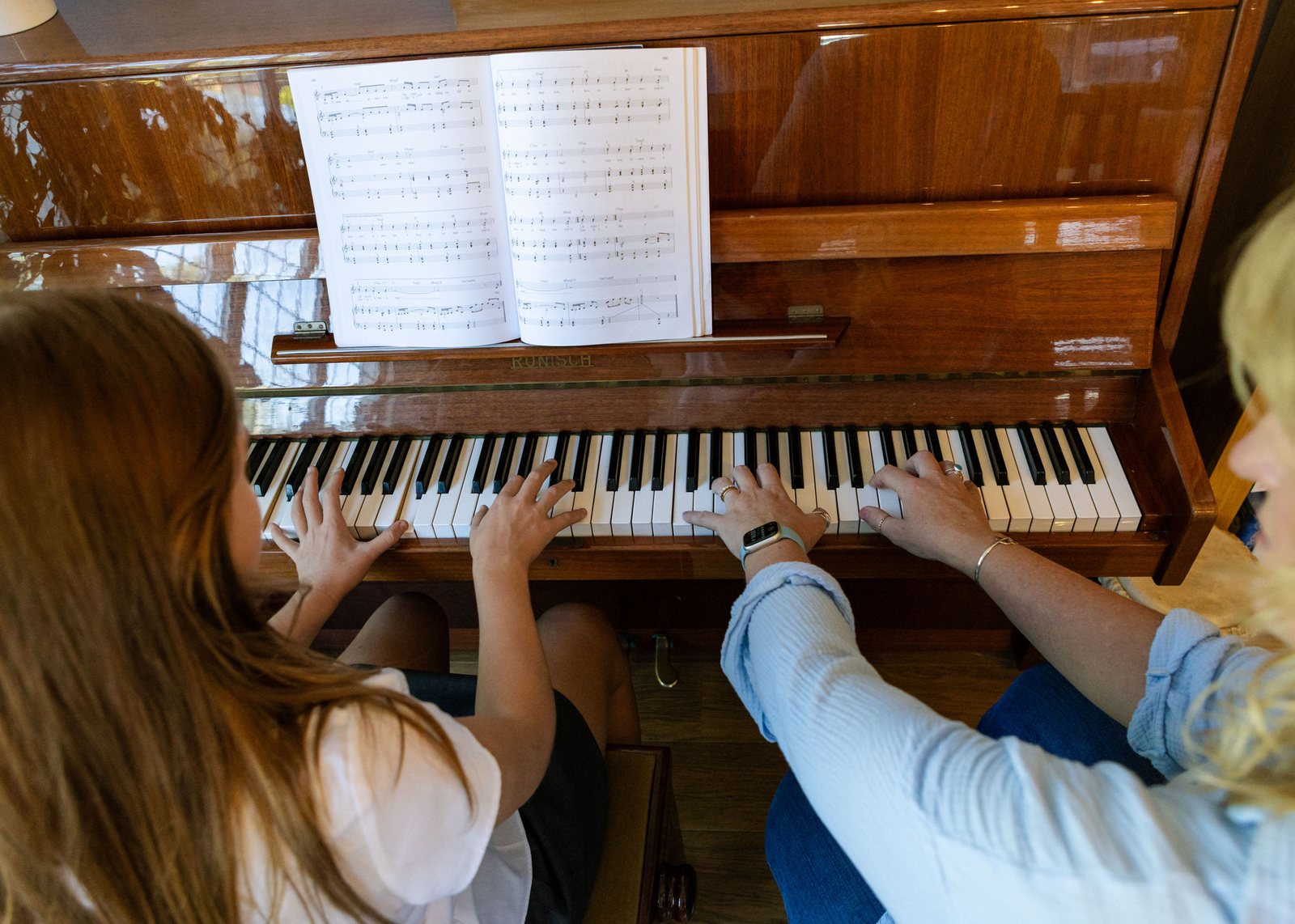 Caroline guiding a student's hands at the piano