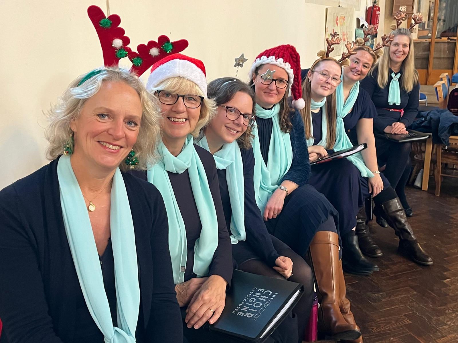 Choir members in festive hats and Sound Engine scarves at a Christmas concert