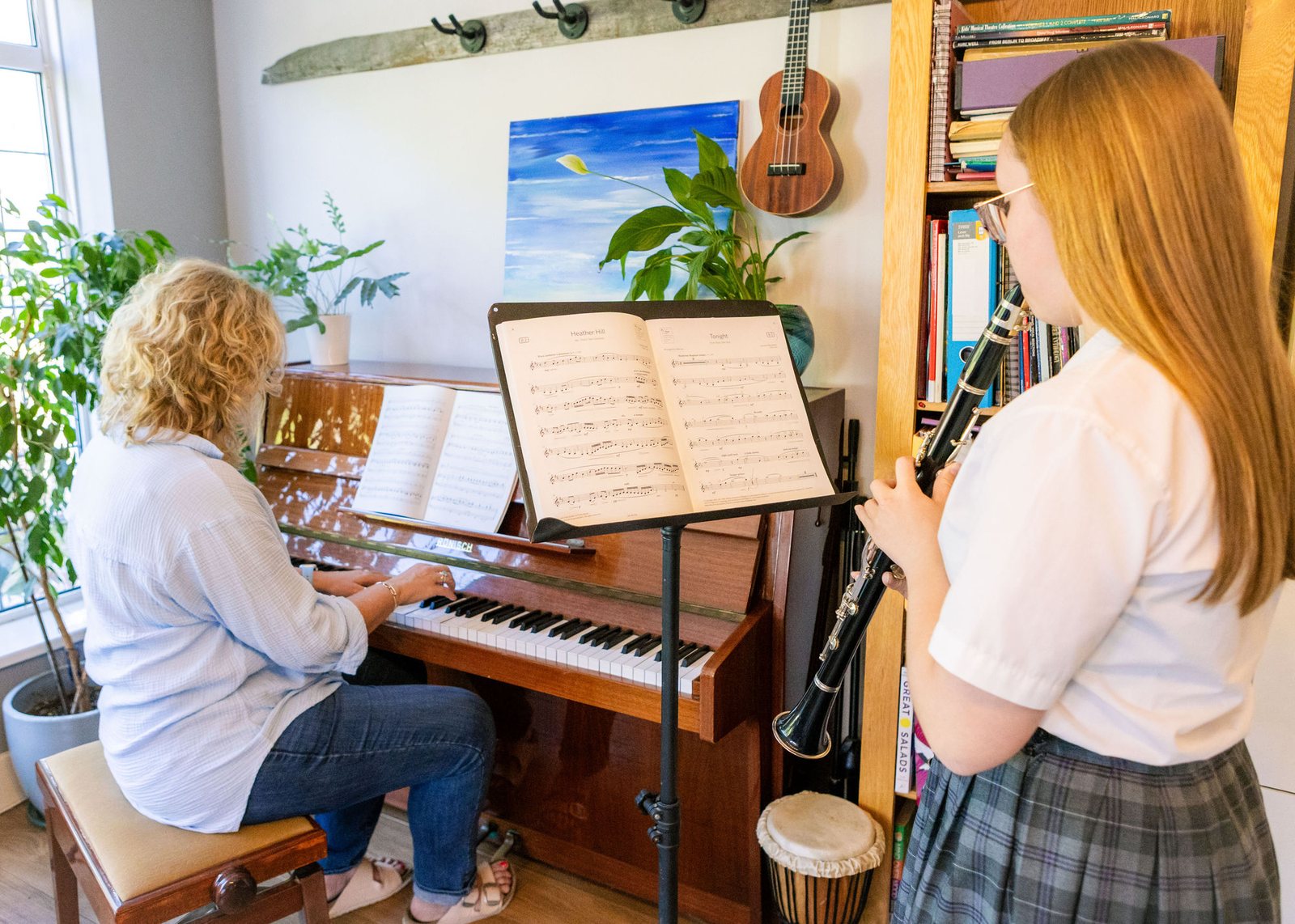 A young pianist playing while another pupil listens